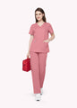 Pink ElegCare™ Essential women's scrub top walking with a red medical bag by COMENII