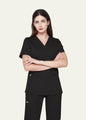 Black SoftTouch™ Essential women's scrub top on model, front view with arms folded by COMENII