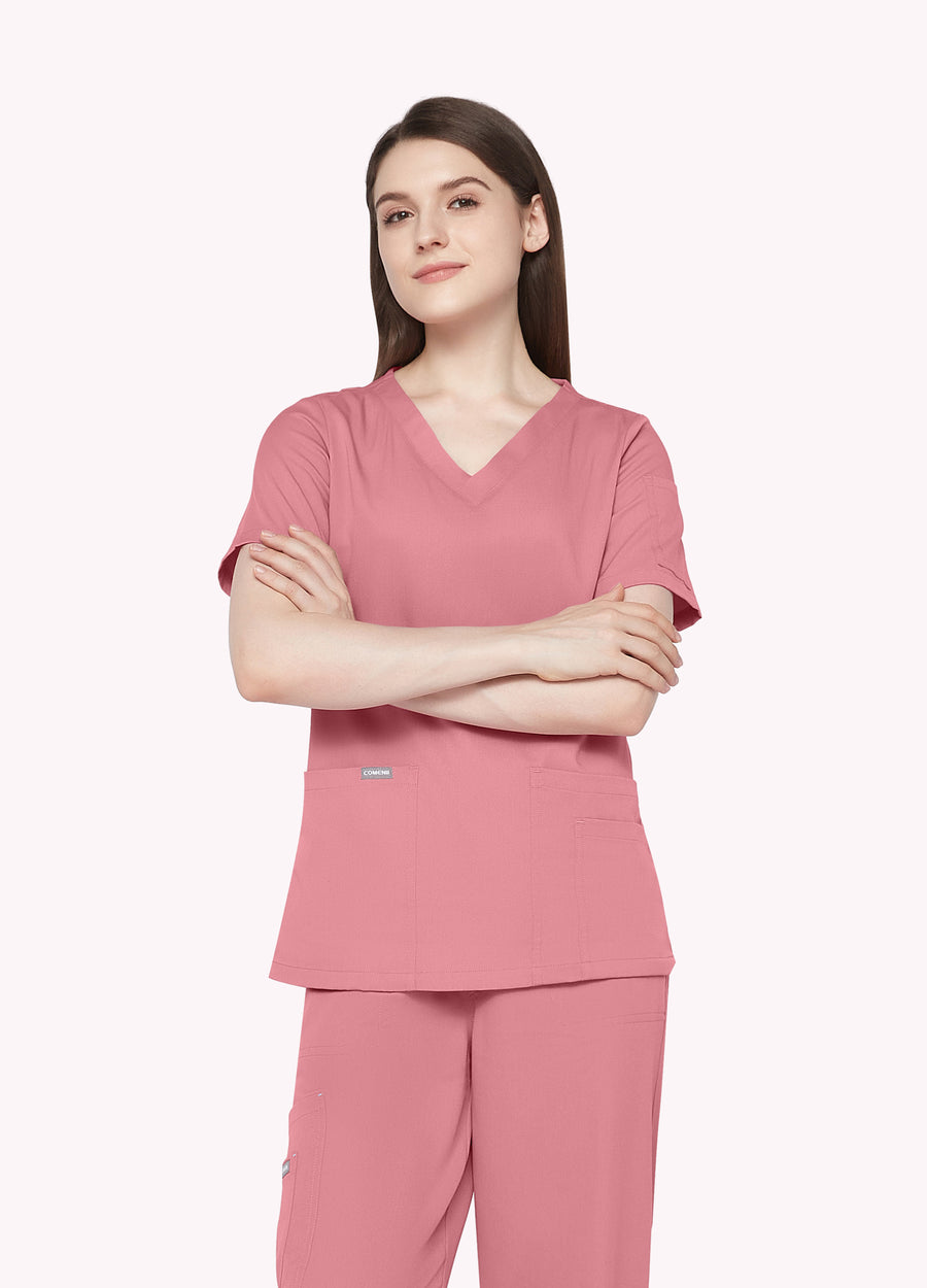 Pink ElegCare™ Essential women's scrub top front view with arms folded by COMENII
